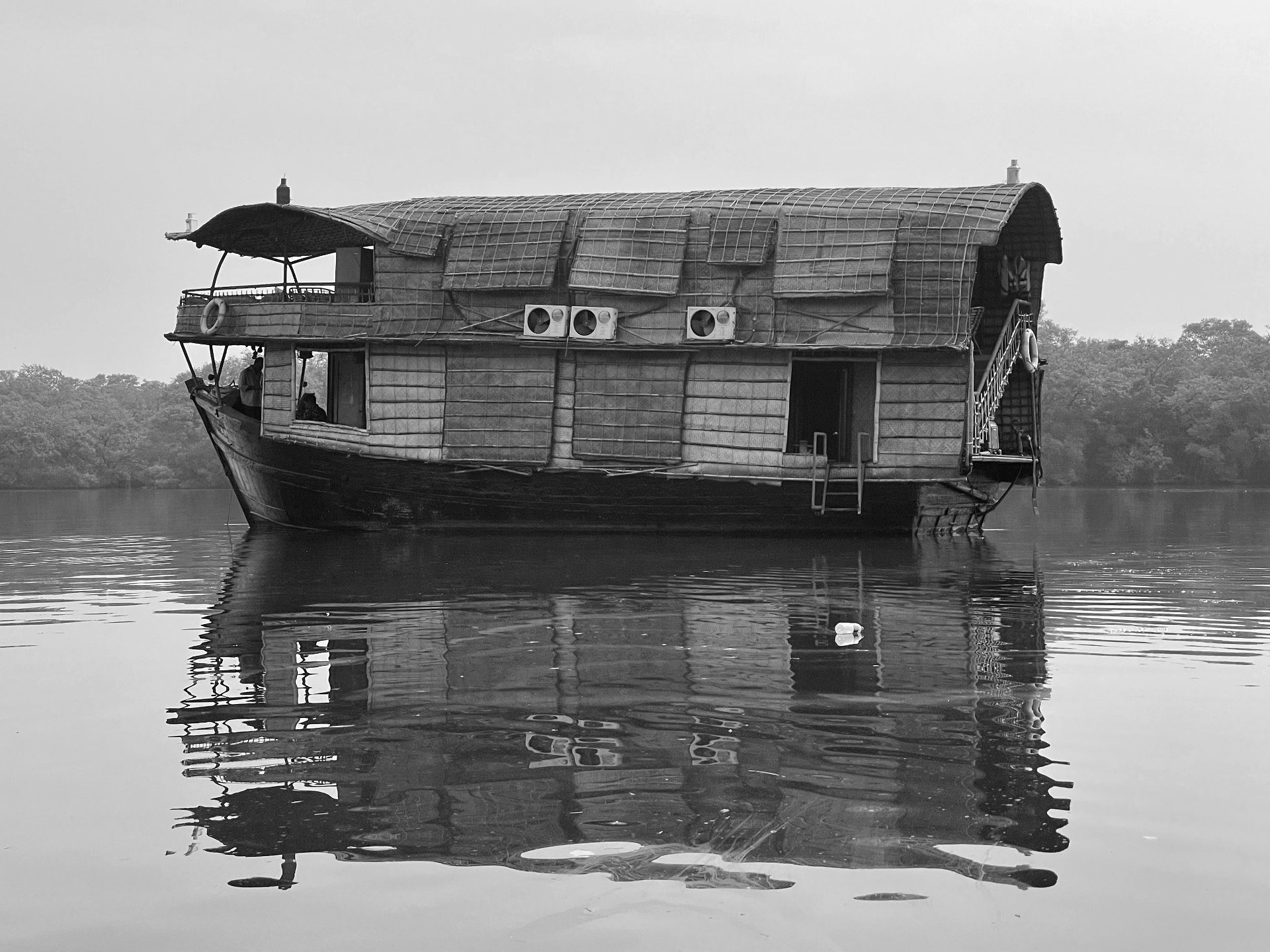 A traditional thatched houseboat moored on the still water of the Goa backwaters