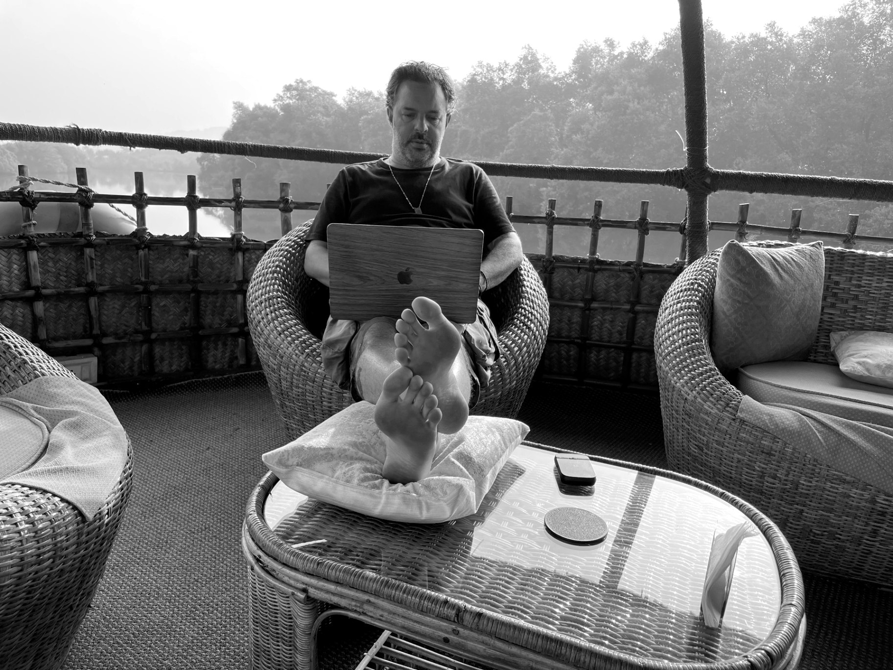 Paul Wakefield writing on a laptop with his feet up on a traditional boat in the Goa backwaters
