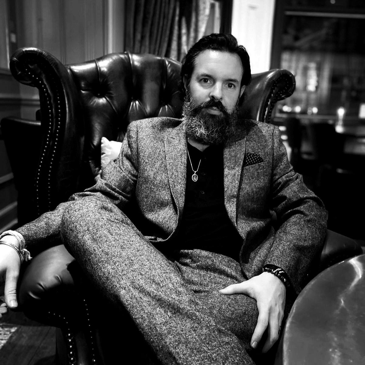 Paul Wakefield seated in a leather armchair wearing a tweed suit