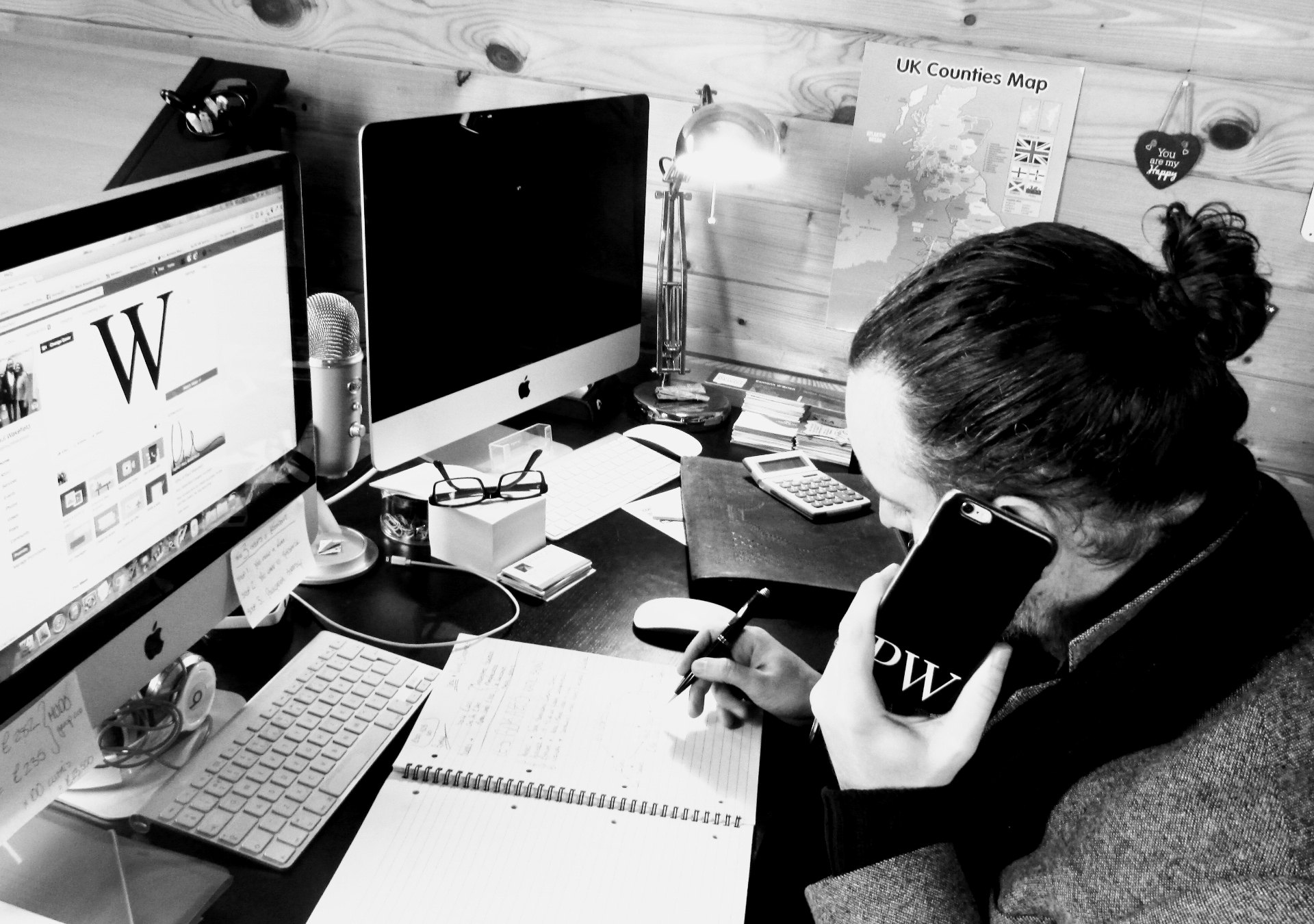 Paul Wakefield working at his home office desk with a notebook, microphone and phone